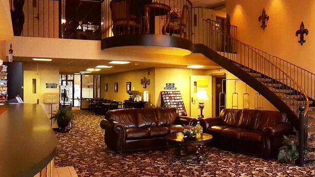 A lobby with a staircase, leather sofas, a reception desk, and a dining area. - Gold Vault Inn (Radcliff)