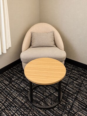 A corner room with a single round table and a cushioned chair. - Gold Vault Inn (Radcliff)