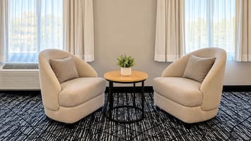 A room with two armchairs, a small round table with a plant, and a radiator.