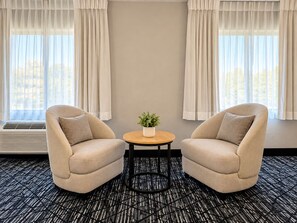 Una habitación con dos sillones, una mesita redonda con una planta y un radiador.