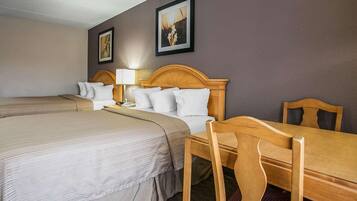 Quarto de hotel com duas camas, uma mesa de madeira e uma cadeira.