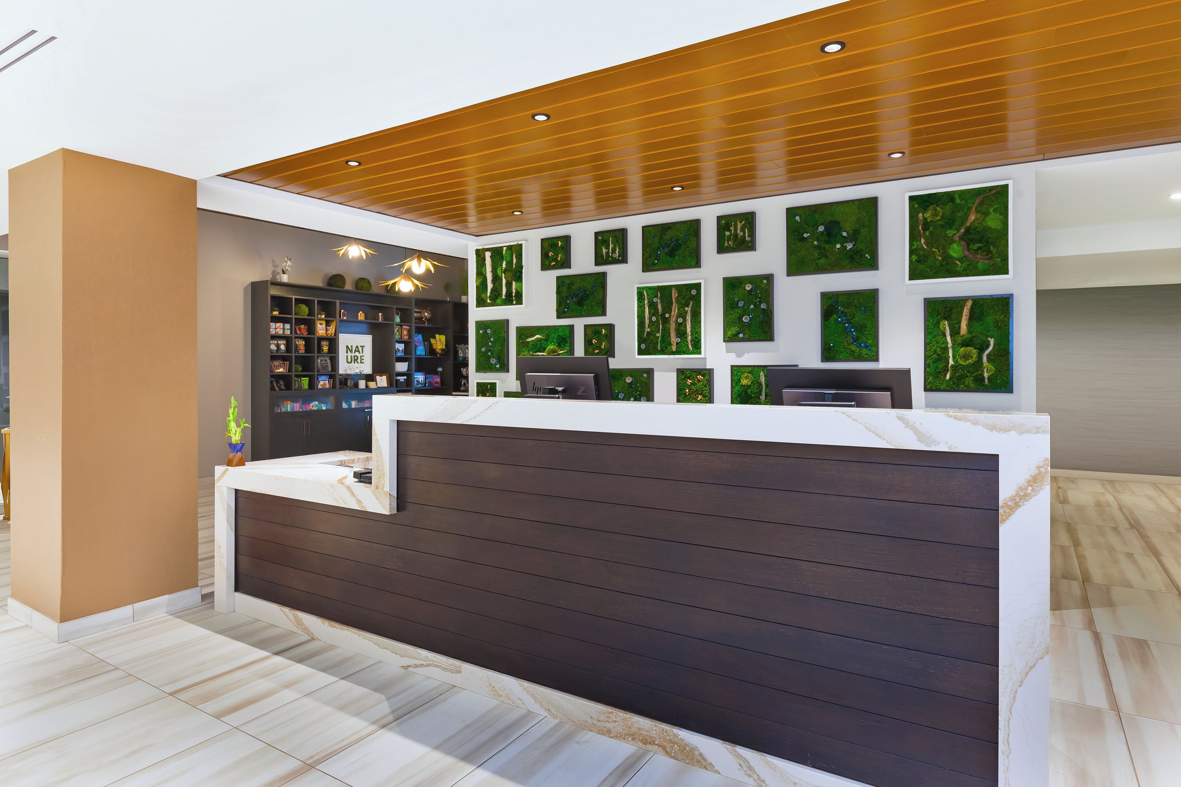A reception desk with a modern design, a wall-mounted aquarium, and a series of framed nature-themed artworks.