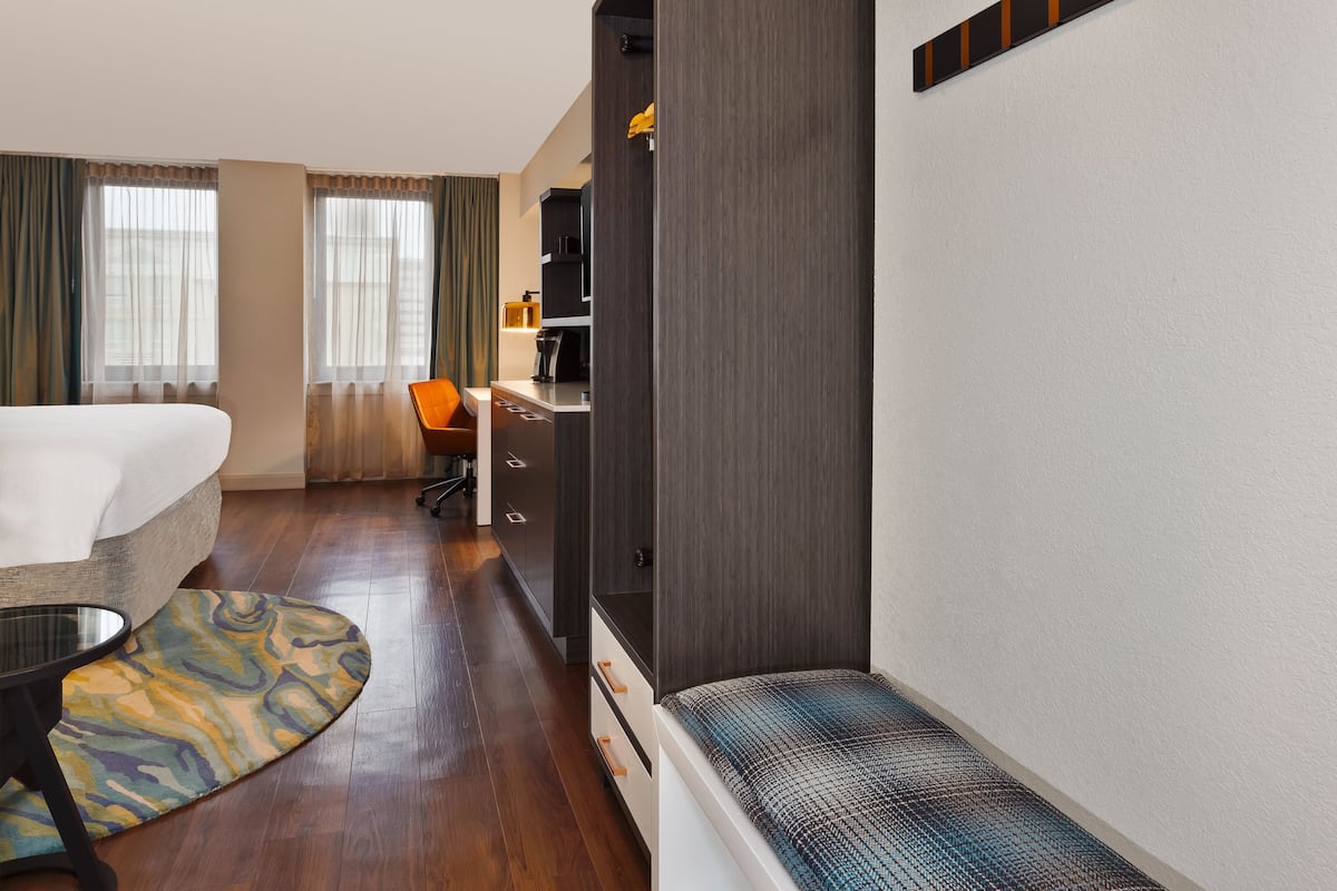Une chambre d’hôtel comprenant un lit, un bureau, une chaise et un petit coin salon.