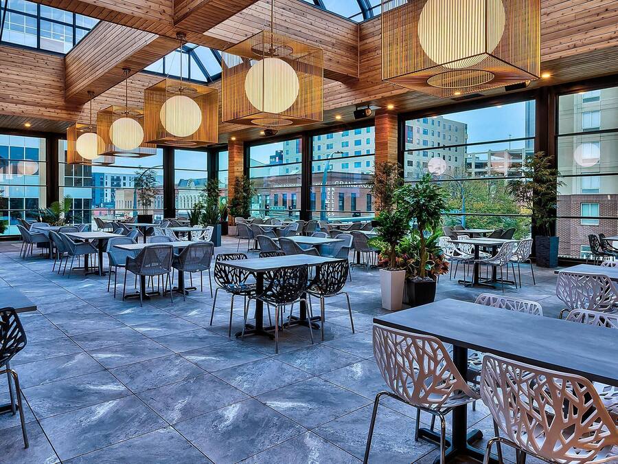 Un amplio espacio al aire libre para comer con muebles modernos y grandes ventanales que ofrecen vistas de la ciudad.