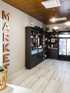 A modern interior with a wooden ceiling, a large black shelving unit, and a refrigerator stocked with beverages. - Hotel Indigo Rochester – Mayo Clinic Area by IHG (Rochester)