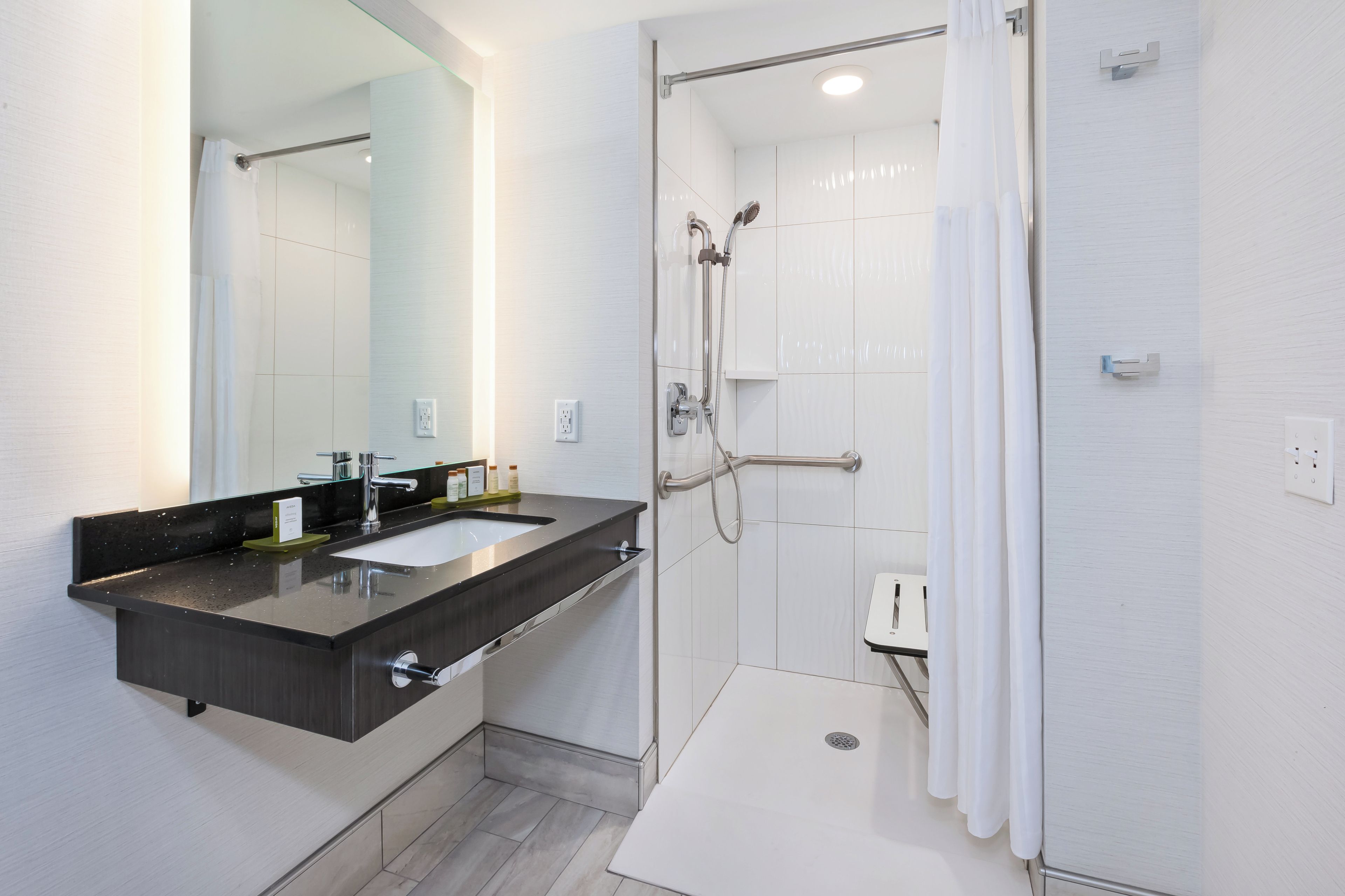 Un bagno moderno con doppio lavabo, doccia con soffione estraibile e specchio con chiusura in vetro.