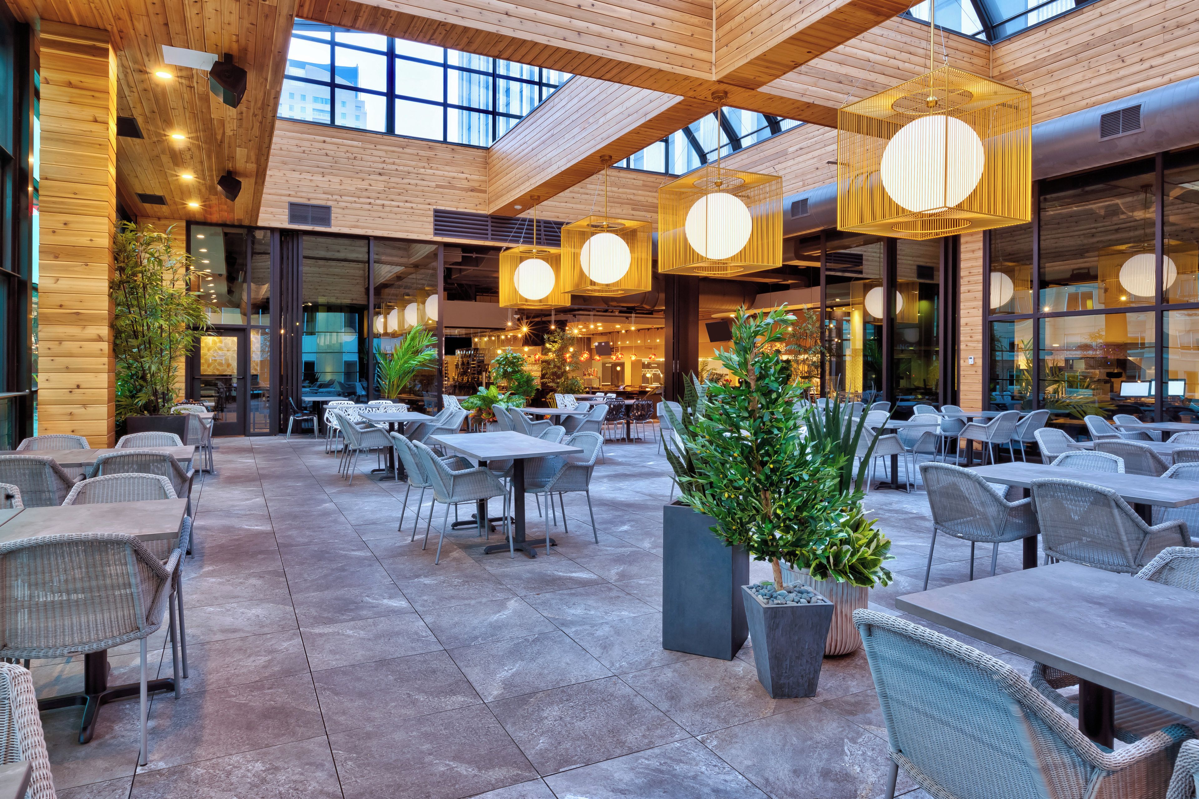 A spacious indoor dining area with high ceilings, wooden beams, and modern pendant lighting.