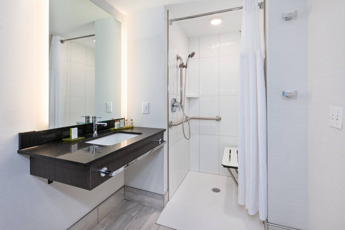 Une salle de bain moderne dotée d’un meuble-lavabo à deux vasques, d’une douche à l’italienne et d’un grand miroir.