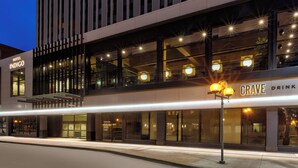 Een modern hotel met een opvallend 'Hotel Indigo' bord, een 'Crave Drink' restaurant en een goed verlichte gevel.