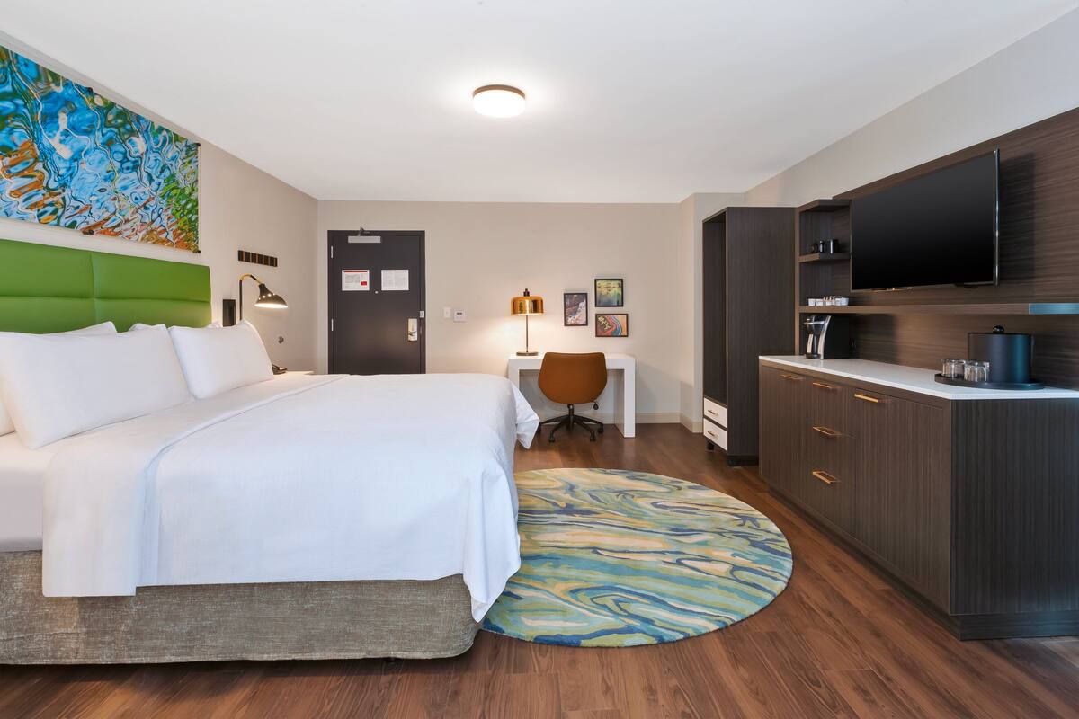 Une chambre d’hôtel équipée d’un lit, d’un bureau, d’une télévision et d’un mini-bar.