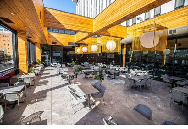 An outdoor dining area with wooden beams, tables, and chairs. - Hotel Indigo Rochester – Mayo Clinic Area by IHG (Rochester)