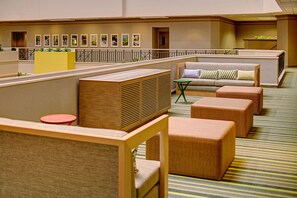 Een hotel lobby met zithoeken, een receptiebalie en een wand met ingelijste foto's.