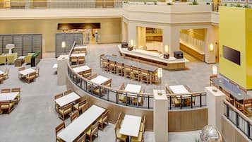 Un hall d’hôtel à plusieurs niveaux, doté d’un atrium central, d’espaces aménagés pour s’asseoir et d’un escalier.