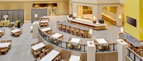 A multi-level hotel lobby with a central atrium, seating areas, and a staircase.