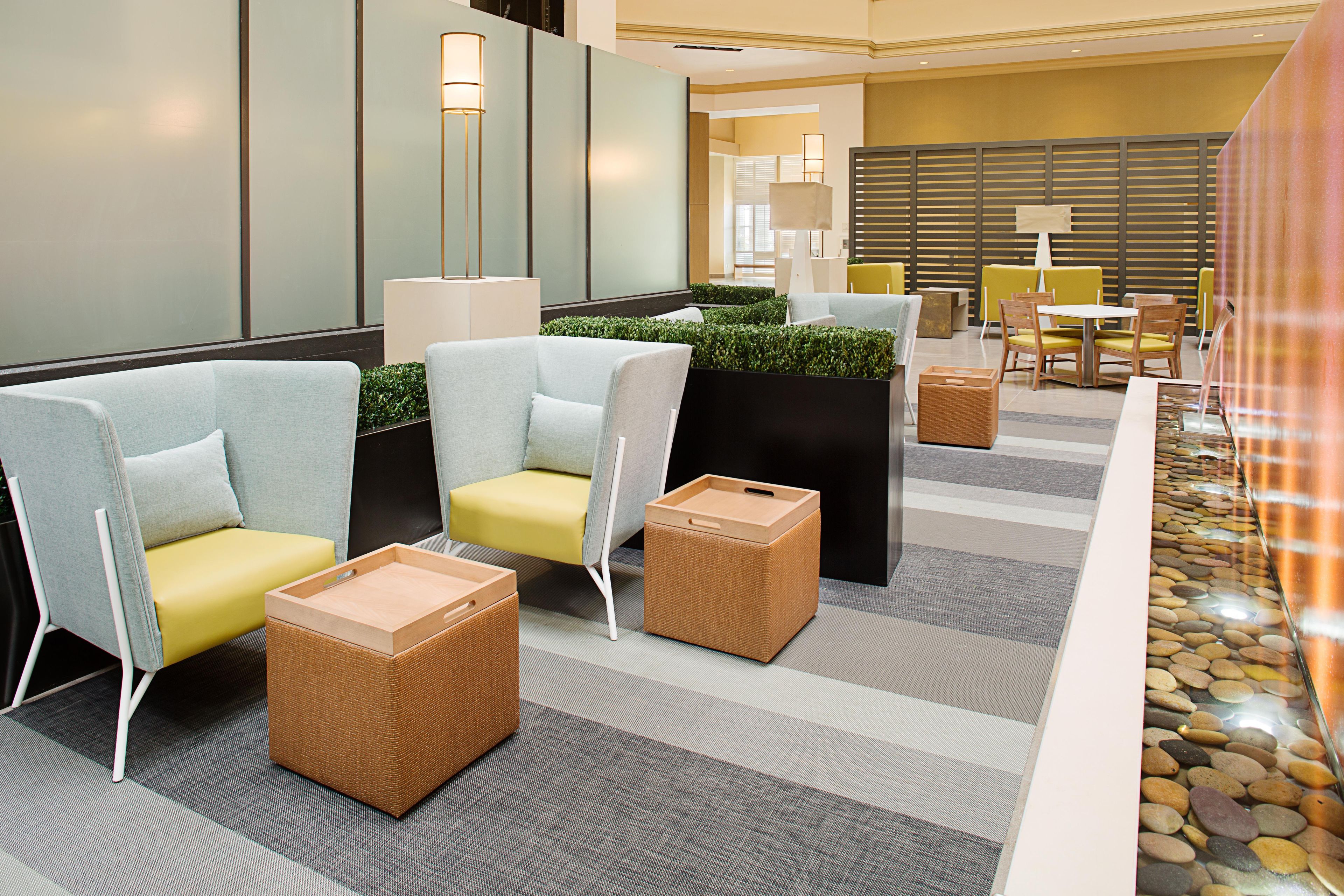 A modern lounge area with seating, a water feature, and a view into the dining area.
