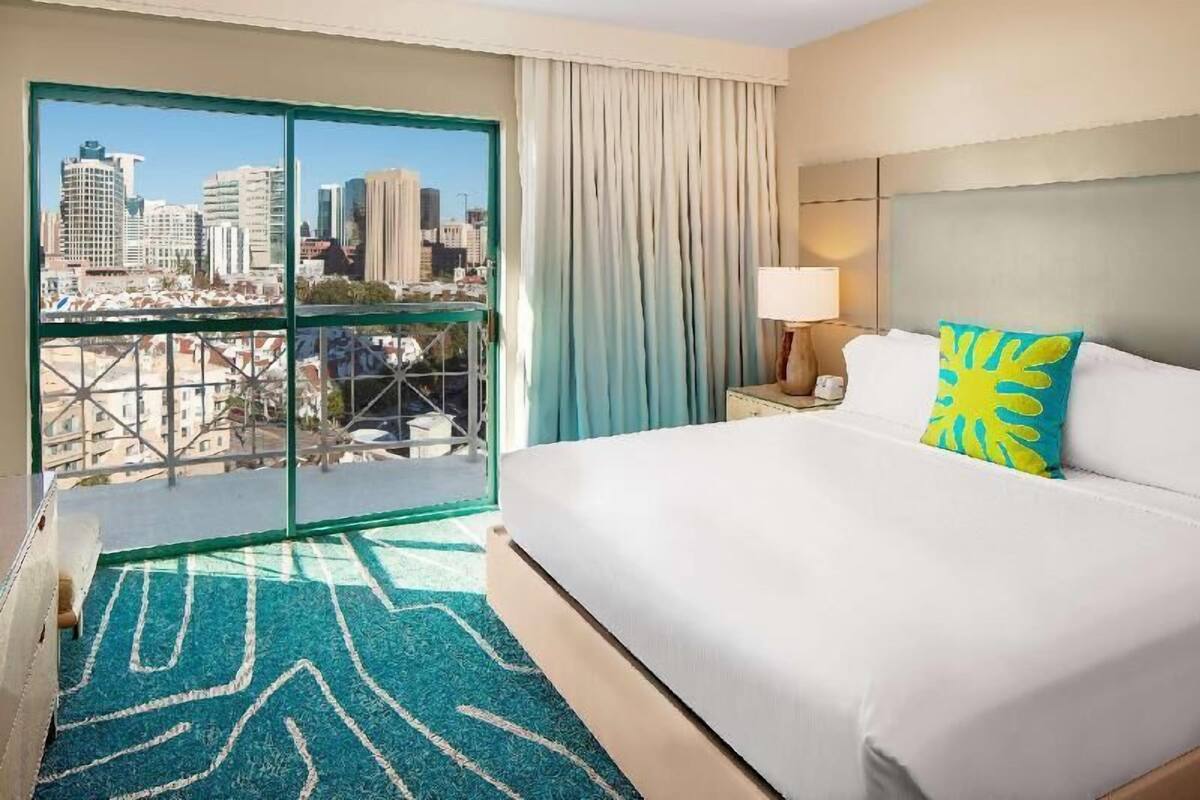 Une chambre d’hôtel avec un grand lit, une vue sur la ville et une fenêtre avec des rideaux.