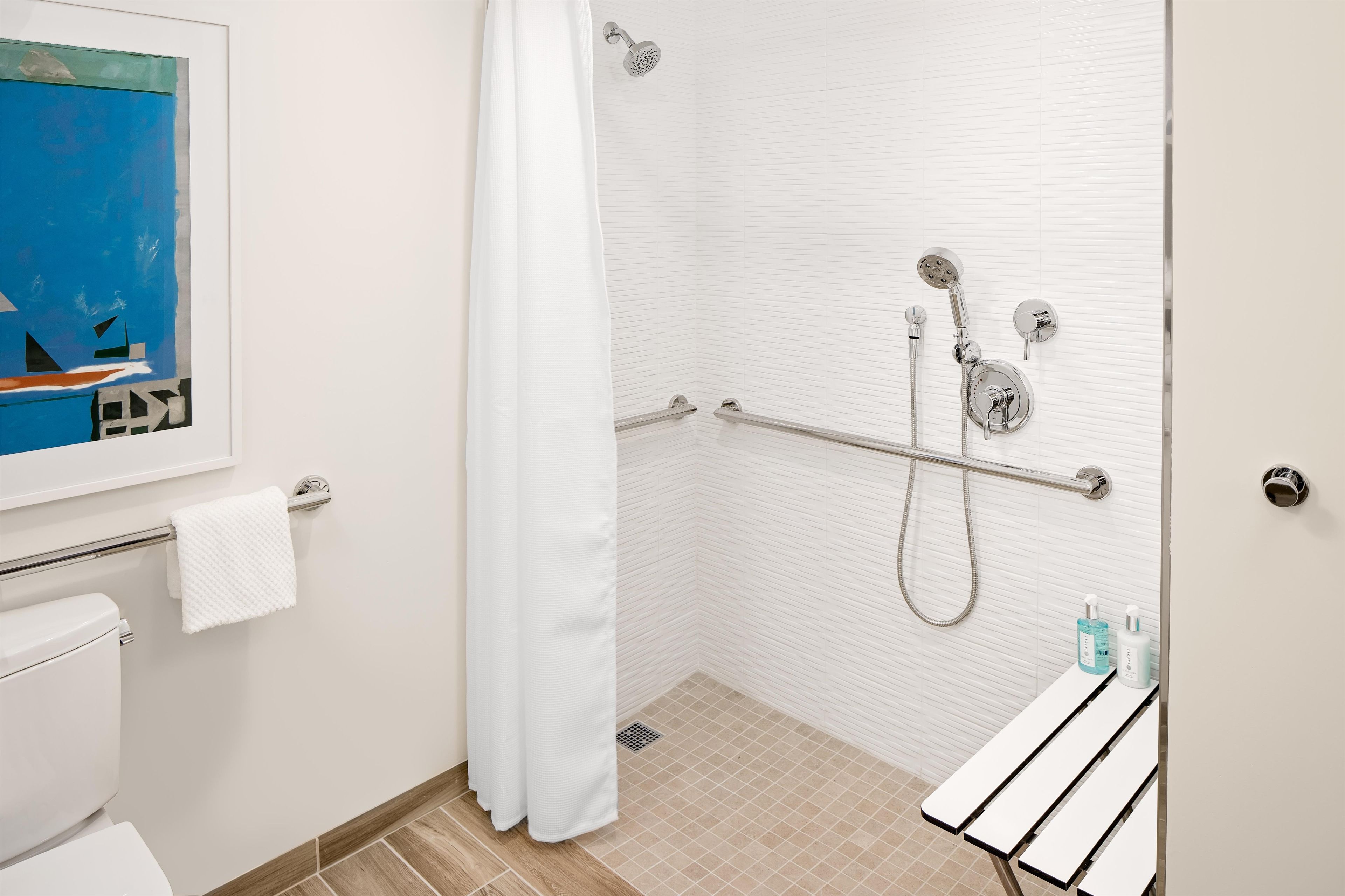 A modern bathroom with a shower, toilet, and a towel rack.