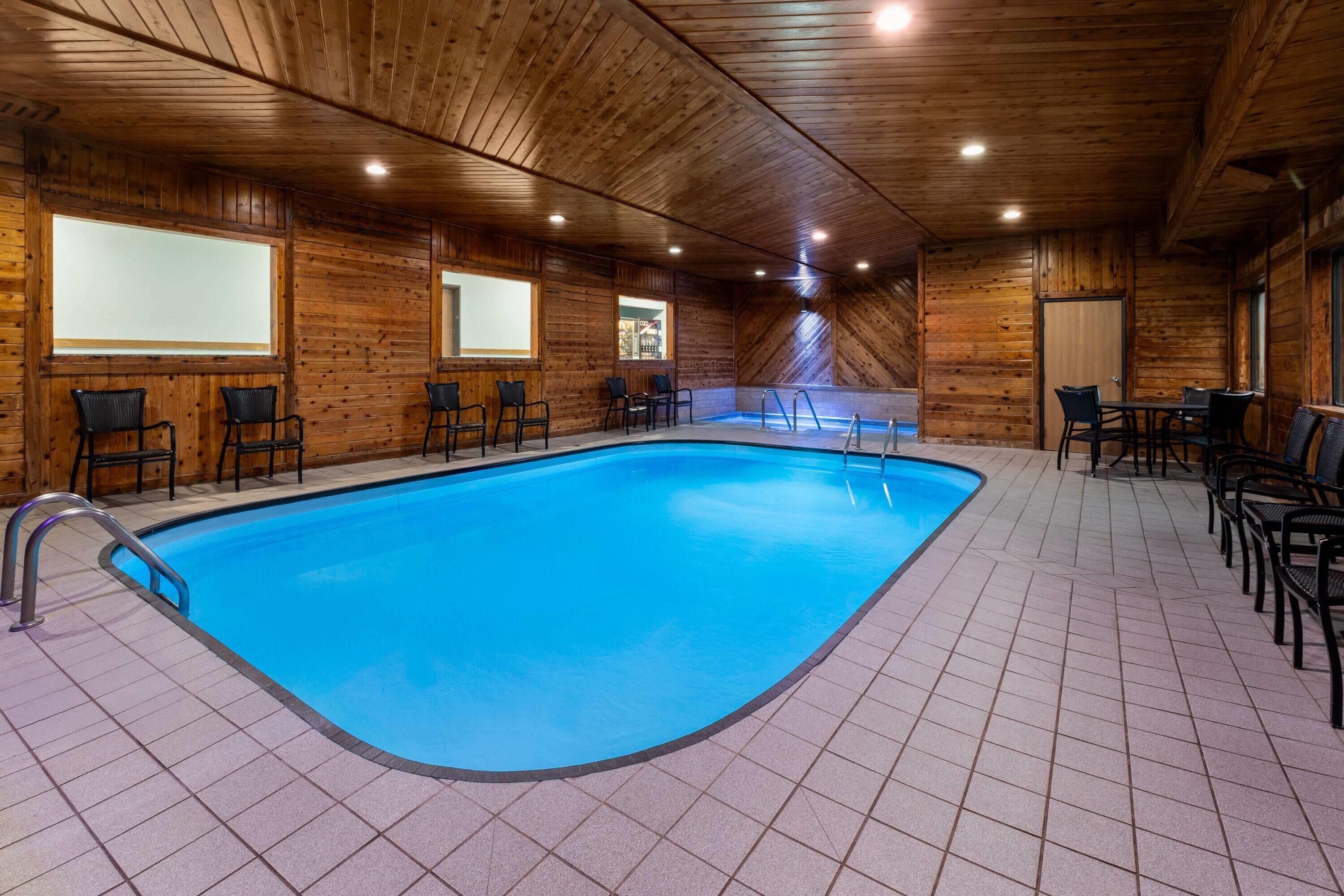 An indoor swimming pool with tiled flooring and wooden walls.