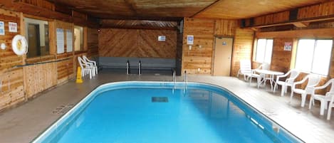 An indoor swimming pool with a wooden interior, a lifeguard chair, and a pool table.