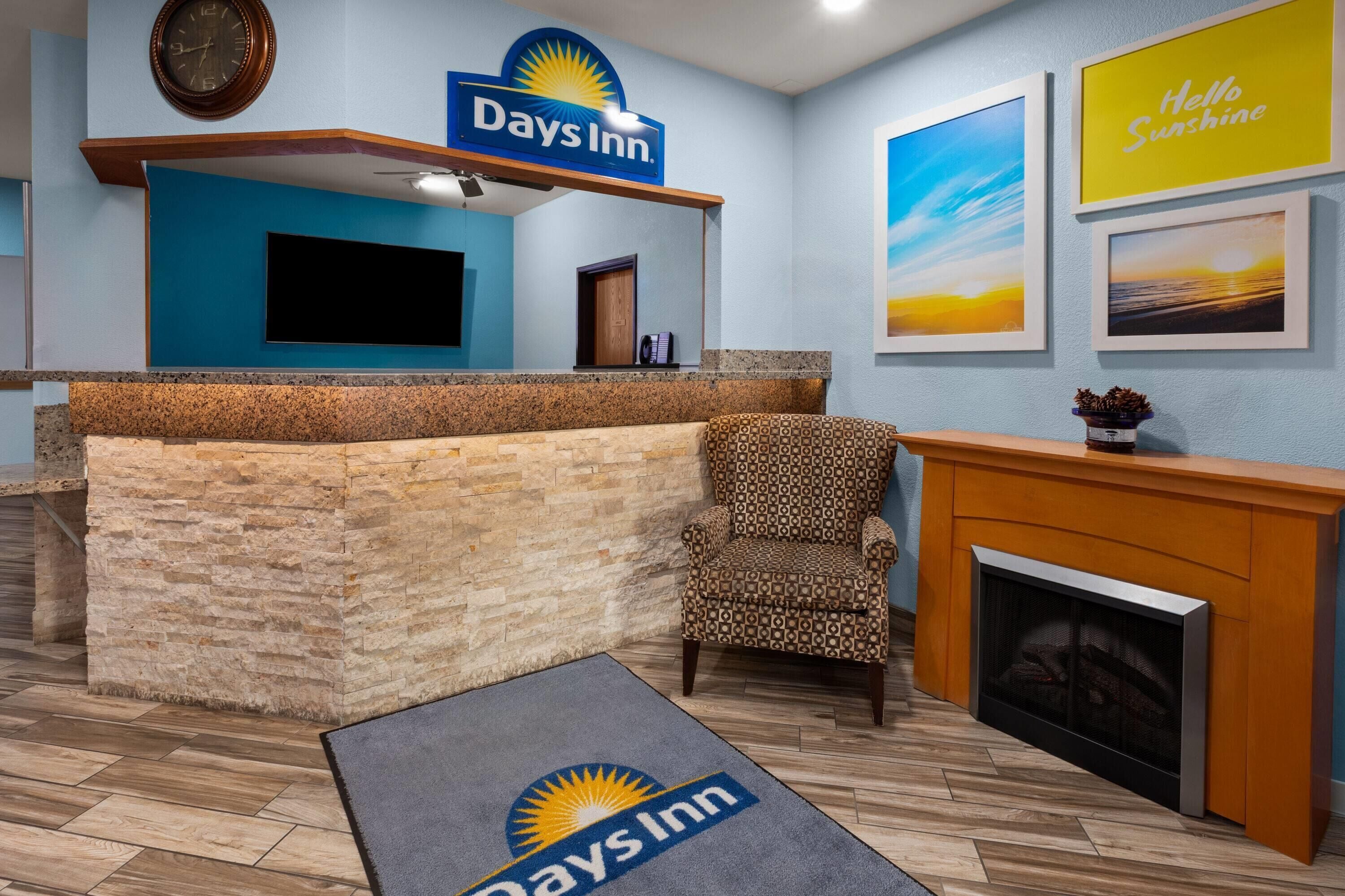 A reception area with a Days Inn sign, a fireplace, and framed artwork on the walls.