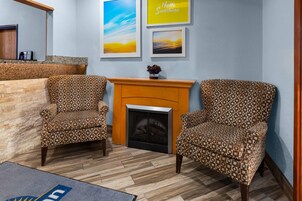 Una habitación con dos sillones estampados, una chimenea y una pared con tres cuadros enmarcados.