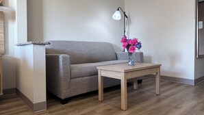 Un salon moderne avec un canapé gris, une table basse en bois et un vase rempli de fleurs roses.