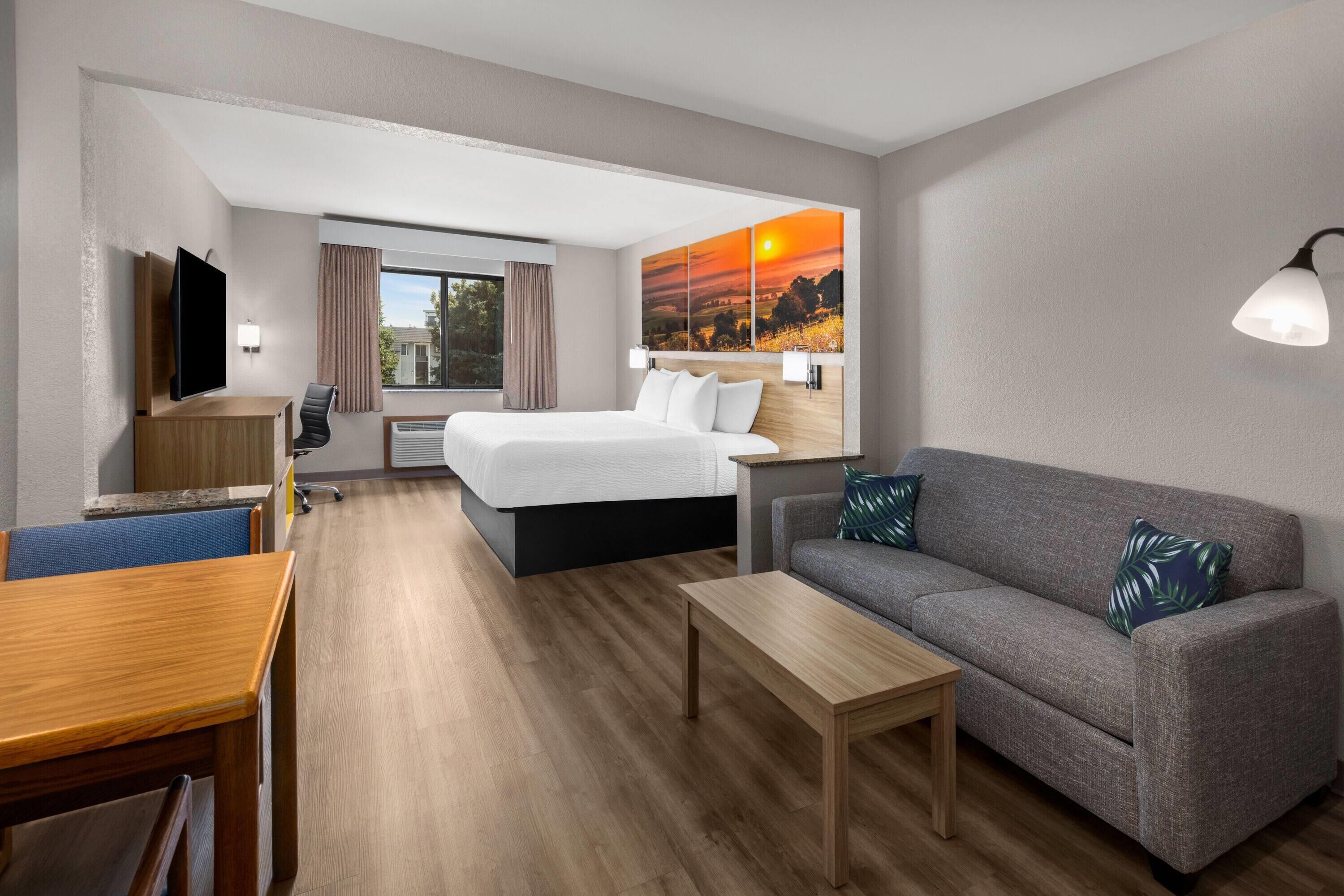 Una habitación de hotel con una cama, un sofá, un escritorio y una televisión.