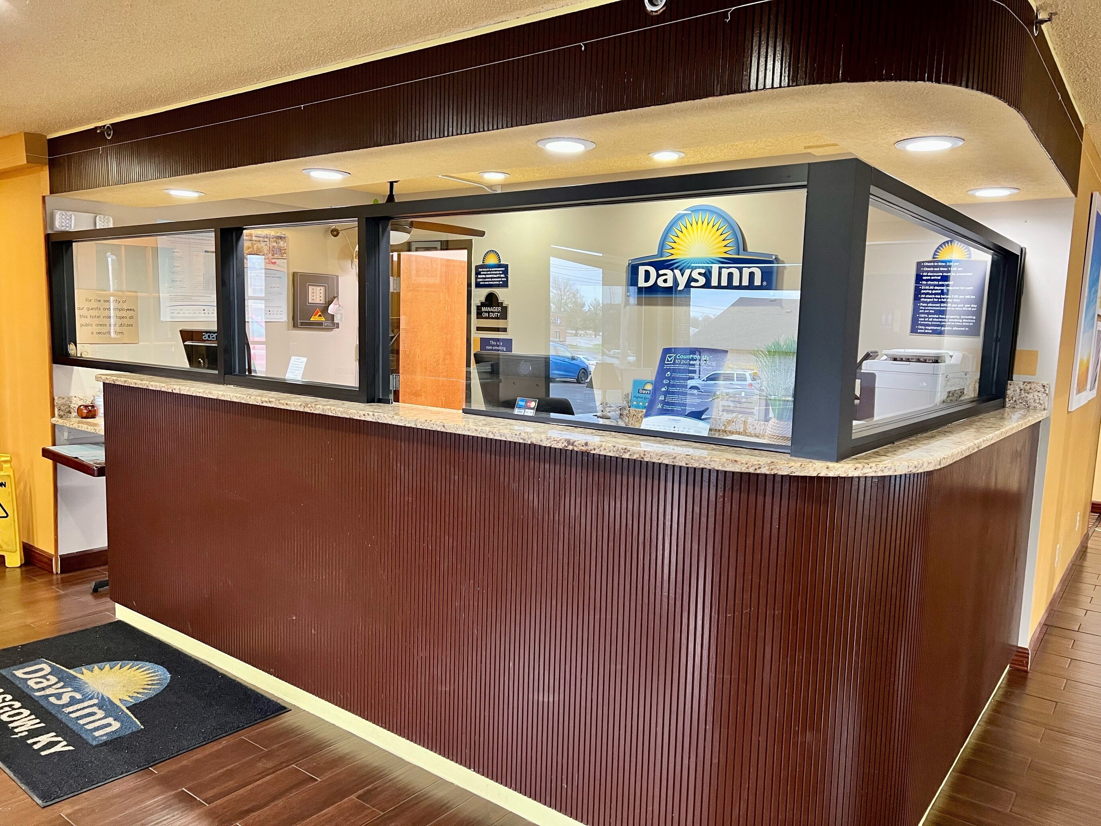 A reception desk with a Days Inn logo, a security camera, and a sign indicating a manager on duty.