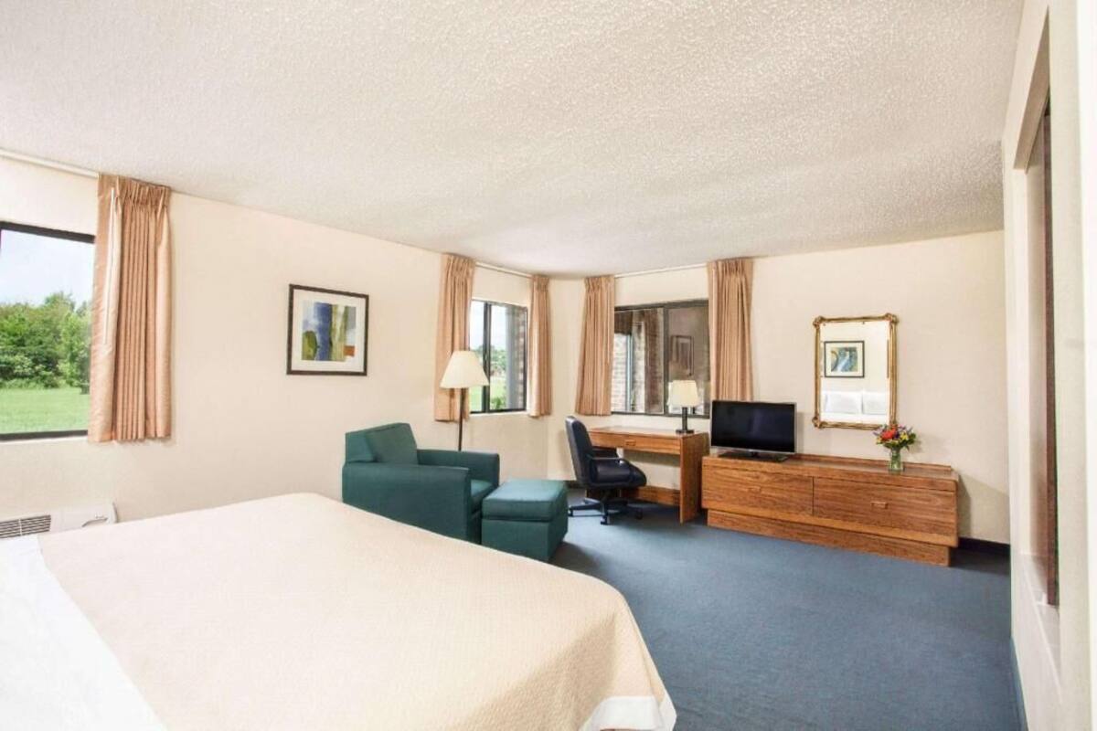 Hotellihuone, jossa on sänky, työpöytä, tuoli ja televisio.