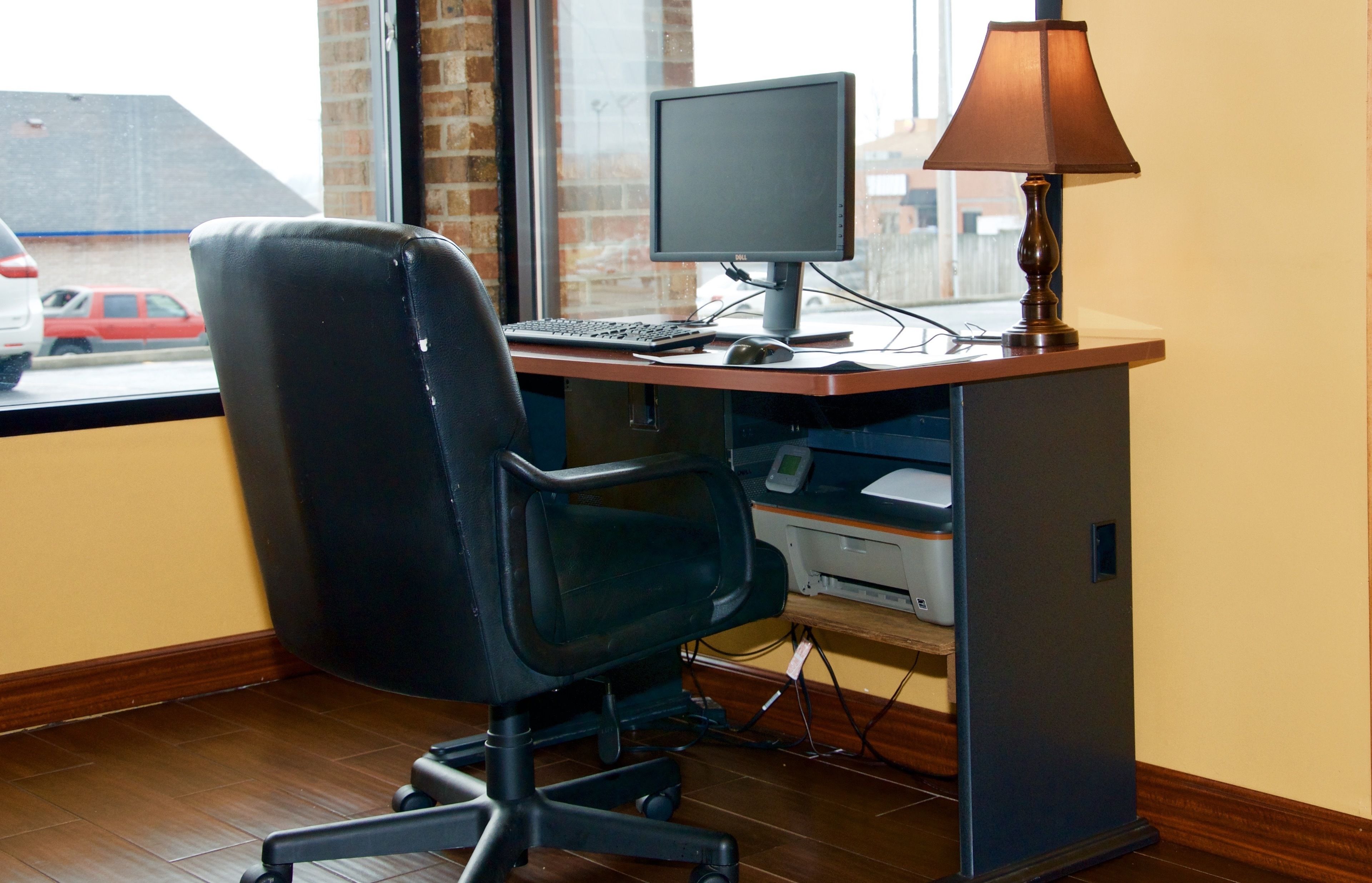 Un espace de travail aménagé à la maison, comprenant un bureau, un ordinateur, une chaise, une lampe et une imprimante.