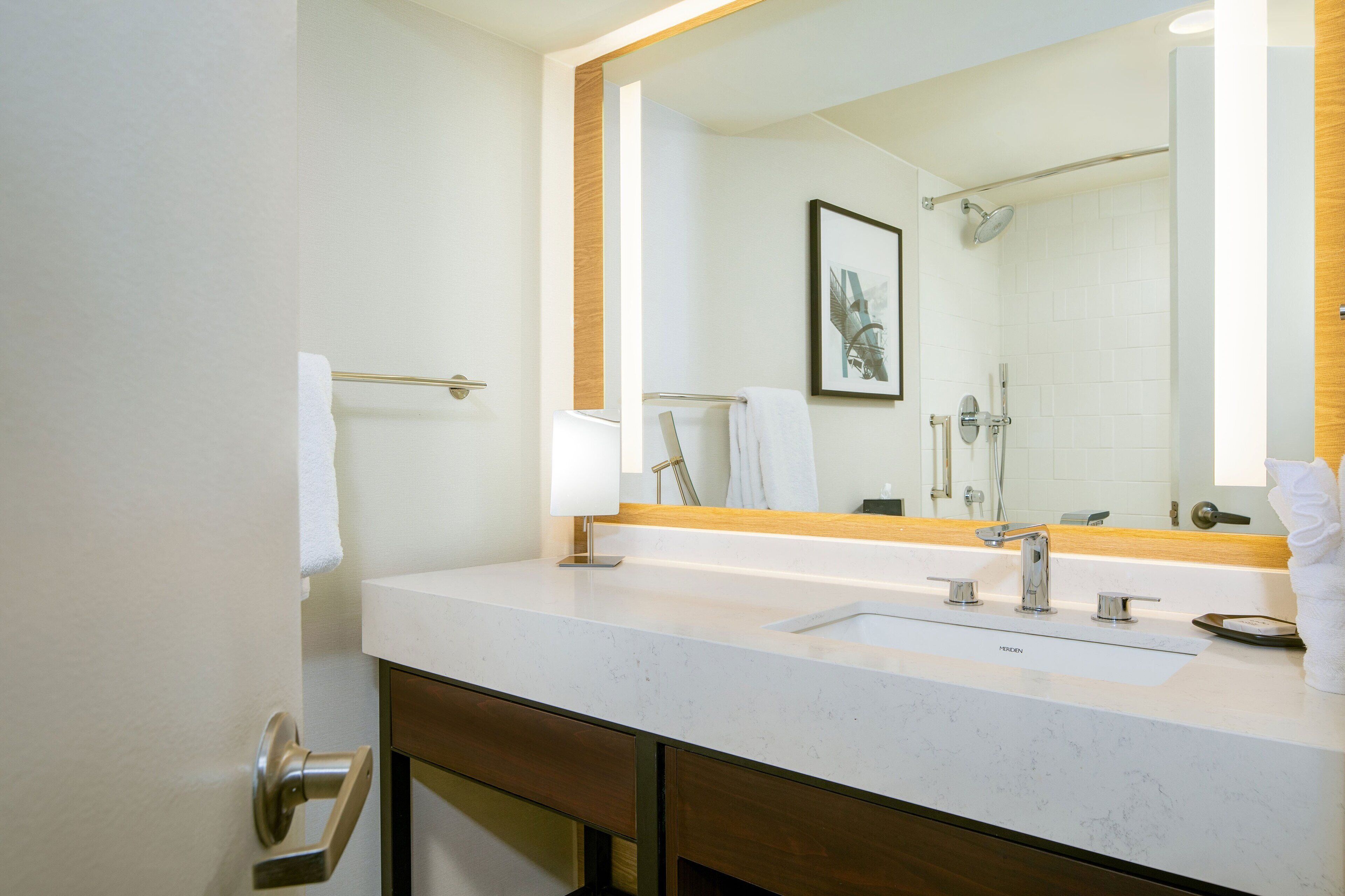 A modern bathroom with a large mirror, a sink, and a shower area.