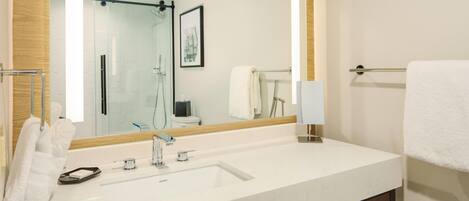Un baño moderno con un espejo grande, lavamanos blanco y tocador de madera.