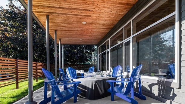Un patio al aire libre con zona cubierta, una mesa y sillas azules.