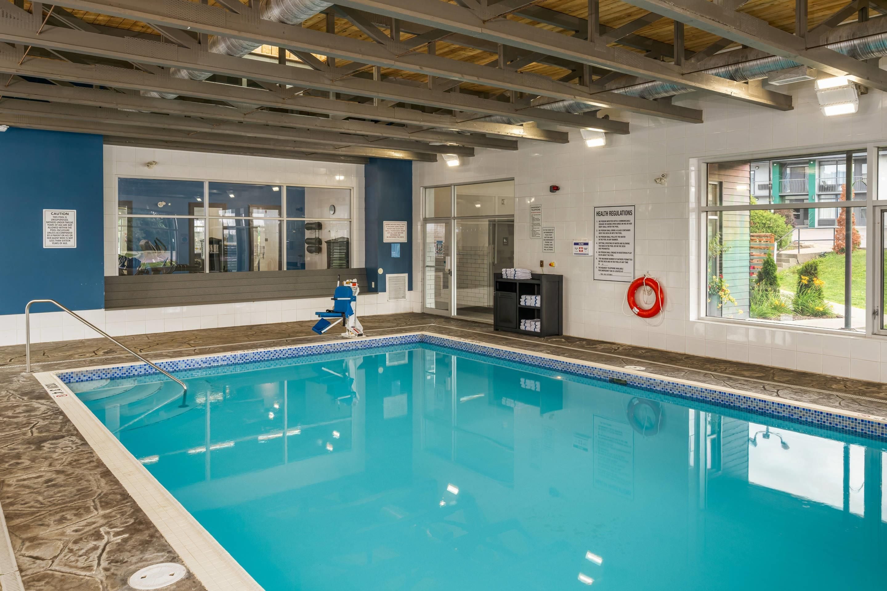Una piscina interior con agua cristalina, un flotador y una silla azul.