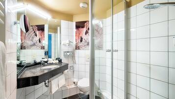 Un baño moderno con cabina de ducha de vidrio, lavamanos de encimera negro y un inodoro.