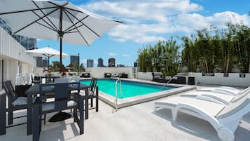 Relax by the pool surrounded by lounge chairs and umbrellas, offering a serene escape with a city view.