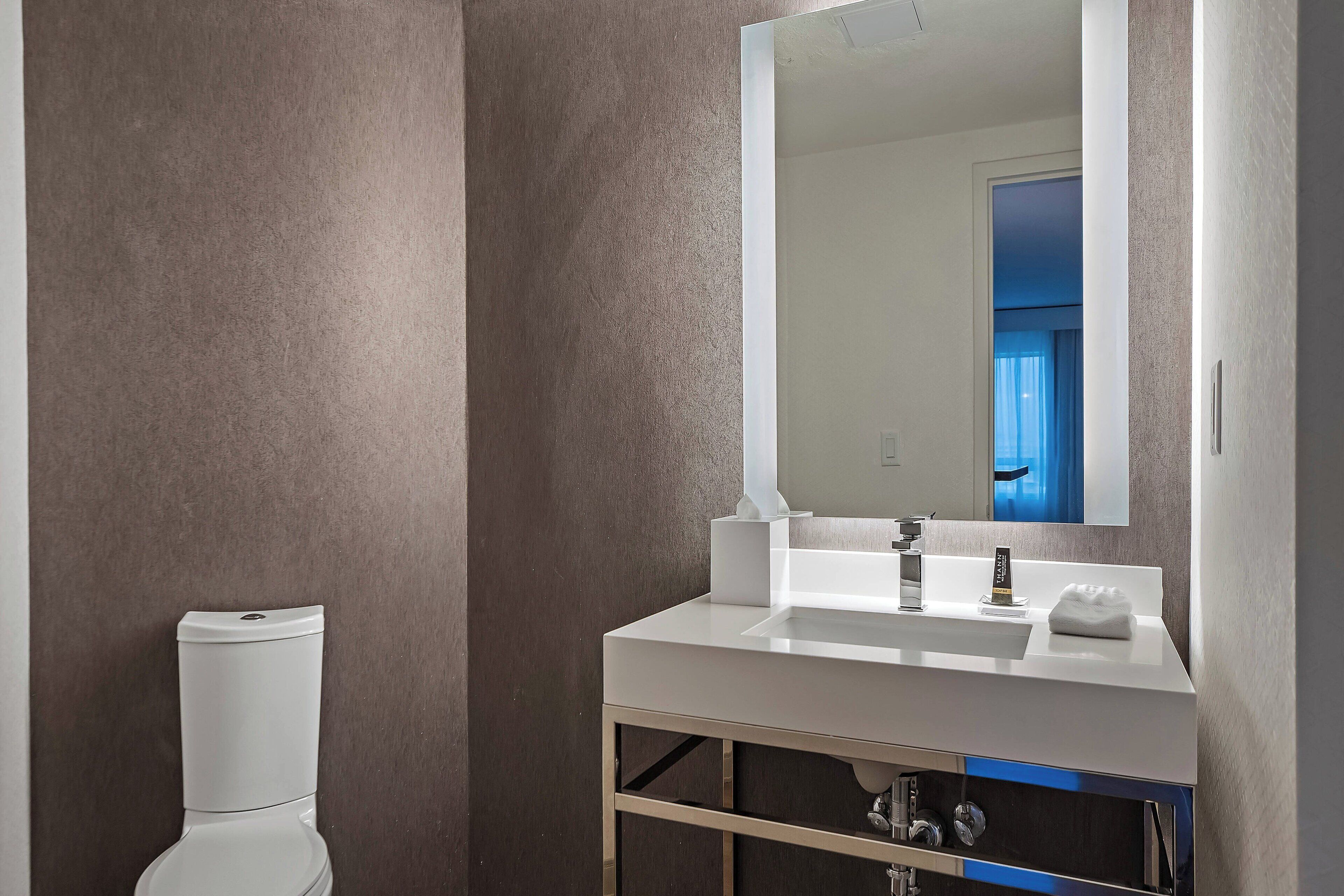 Un baño moderno con un inodoro blanco, un lavabo blanco y un espejo grande.