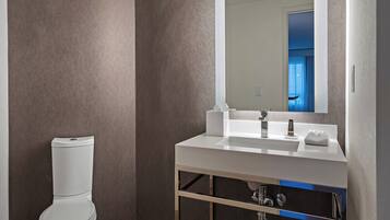 Un baño moderno con un inodoro blanco, un lavabo blanco y un espejo grande.