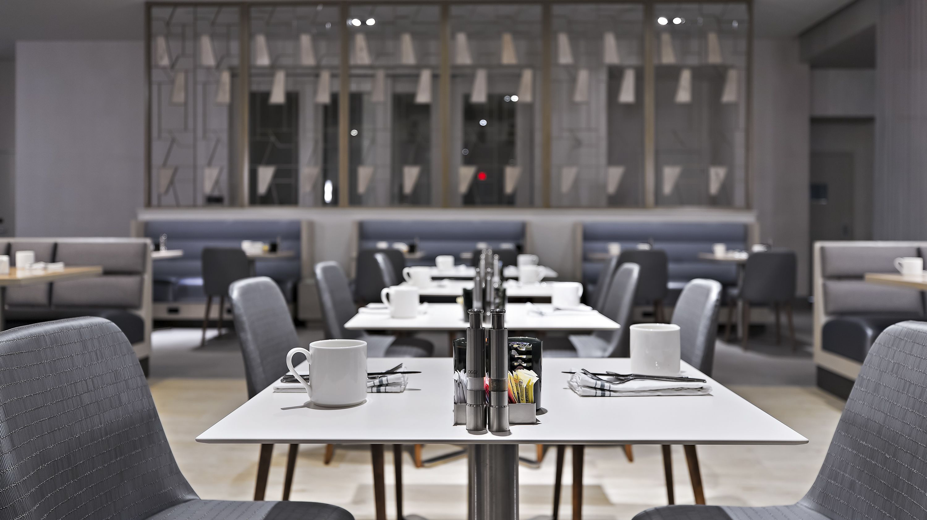Un espace repas moderne avec des tables et des chaises, une machine à café et un luminaire décoratif.
