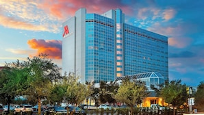 Un hotel moderno con fachada de vidrio llamativa y un logo rojo característico.