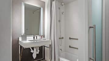 A modern bathroom with a white vanity, a large mirror, a shower with a glass door, and a bathtub.