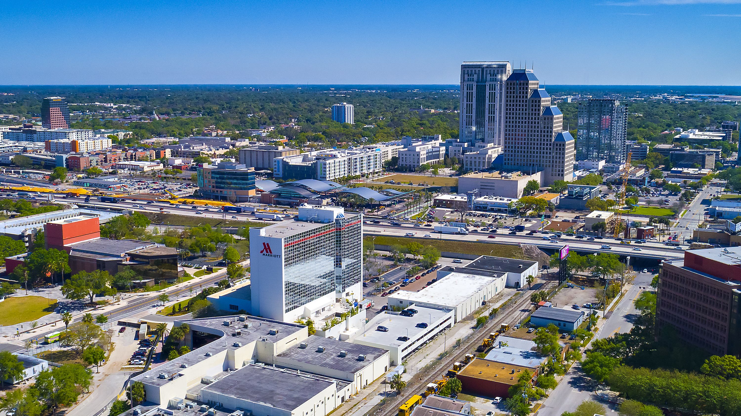 A cityscape with a prominent Marriott hotel, various buildings, roads, and a distant view of the horizon.