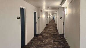A long, narrow hotel hallway with carpeted floors and doors numbered 208, 210, and 209. - Motel 6 Lincoln, NE - Airport (Lincoln)