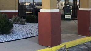 A building entrance with a covered area supported by columns, a large glass door, and a sign for a marketplace. - Motel 6 Lincoln, NE - Airport (Lincoln)