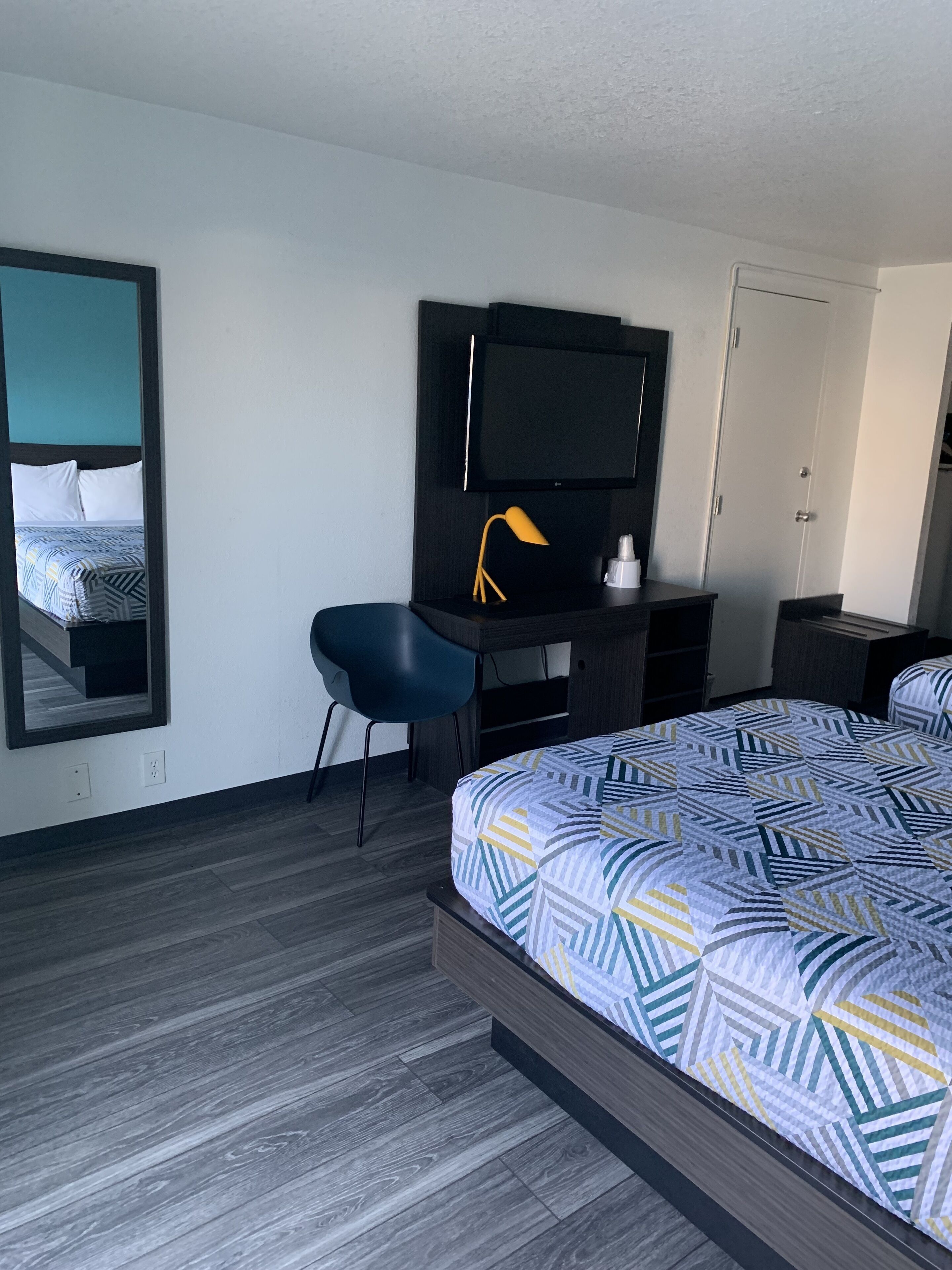 Una habitación de hotel con cama, escritorio con silla, televisor y armario.