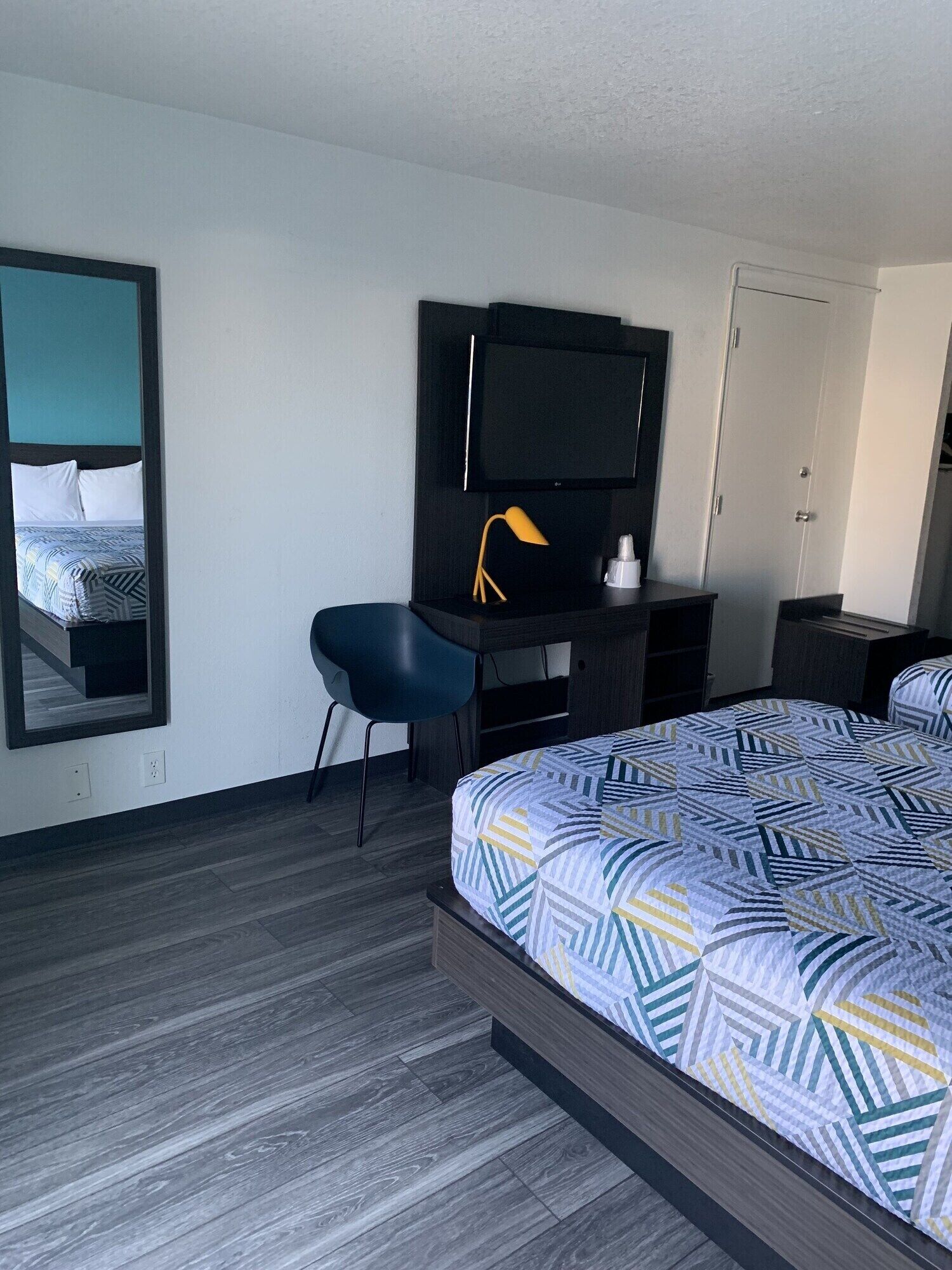Een hotelkamer met een bed, een bureau met stoel, een televisie en een kledingkast.