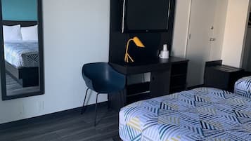 Een hotelkamer met een bed, een bureau met stoel, een televisie en een kledingkast.