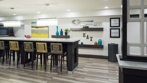 A modern kitchen with a bar area, wooden chairs, and a large island. - Hampton Inn Monterey (Monterey)