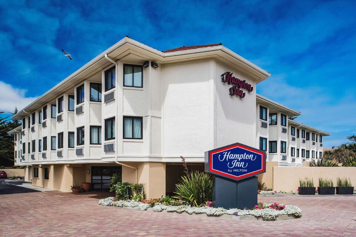 Un hotel Hampton Inn by Hilton con fachada blanca, varias ventanas y un letrero.