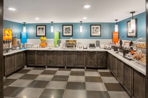 A modern kitchen with a checkered floor, dark wooden cabinets, and a variety of breakfast items on the counter.